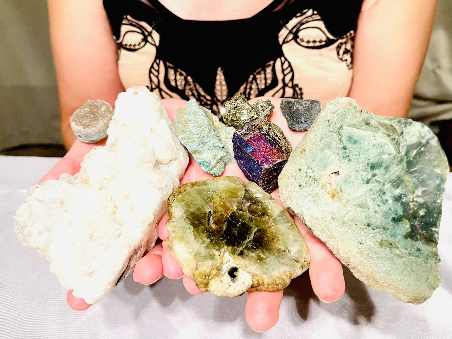 Close up of Tammy Campbell's hands full of several different gemstones of different shapes and sizes.